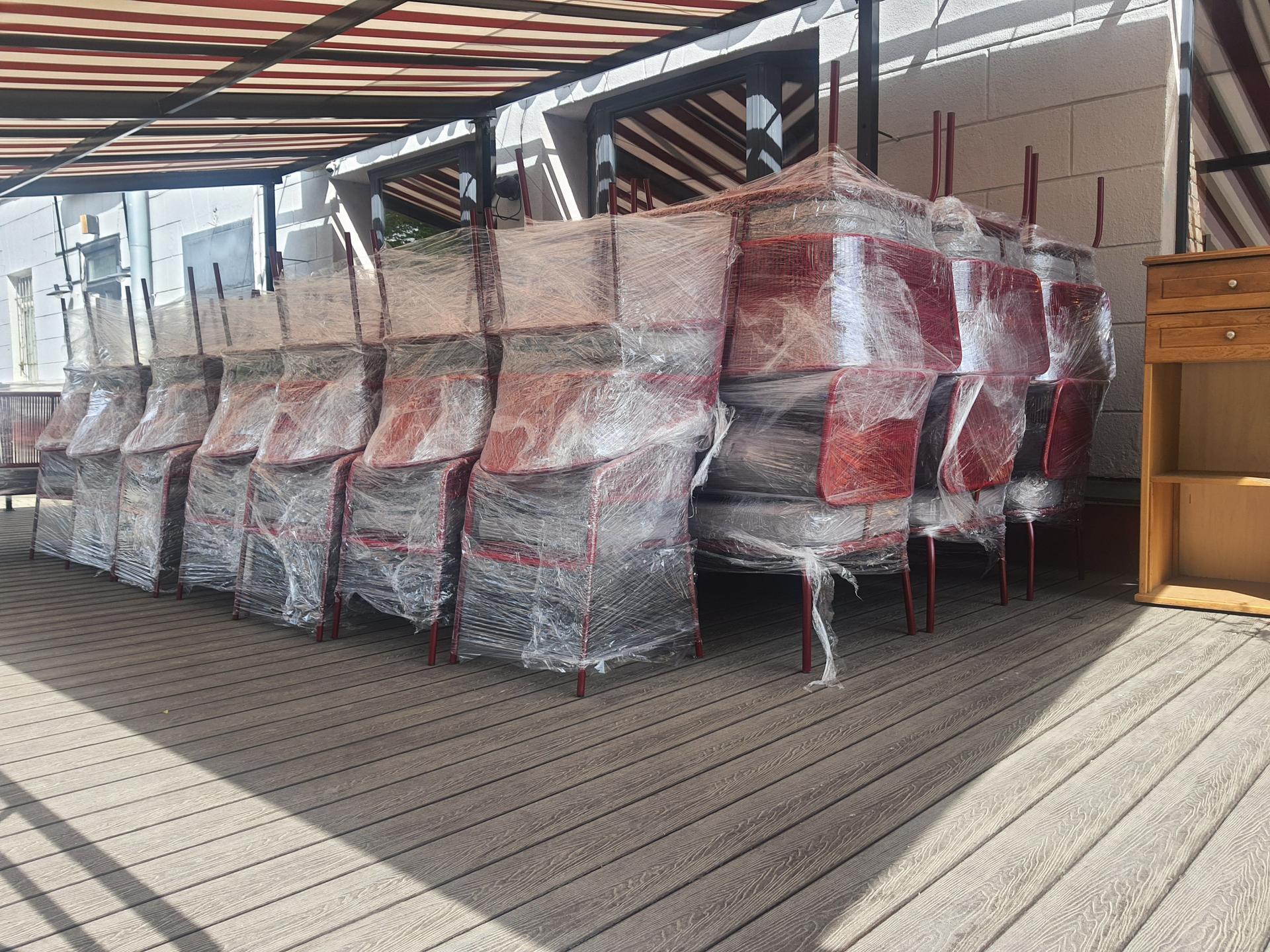 Stacked chairs wrapped in plastic film suggesting closed cafe or restaurant